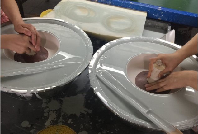 Two workers put ceramic bowls into the glaze dipping bucket..png