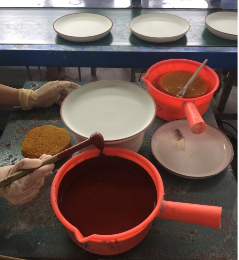 A worker hand tracing the edge of a ceramic plate.png