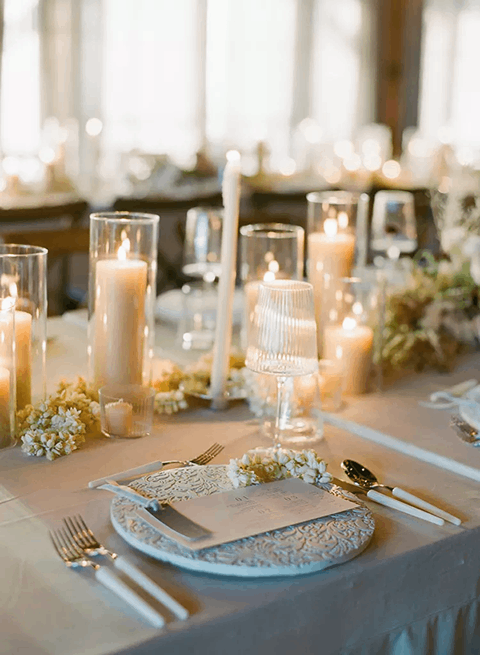 Place-settings-with-white-etched-chargers-ribbed-glassware-white-florals-and-candles